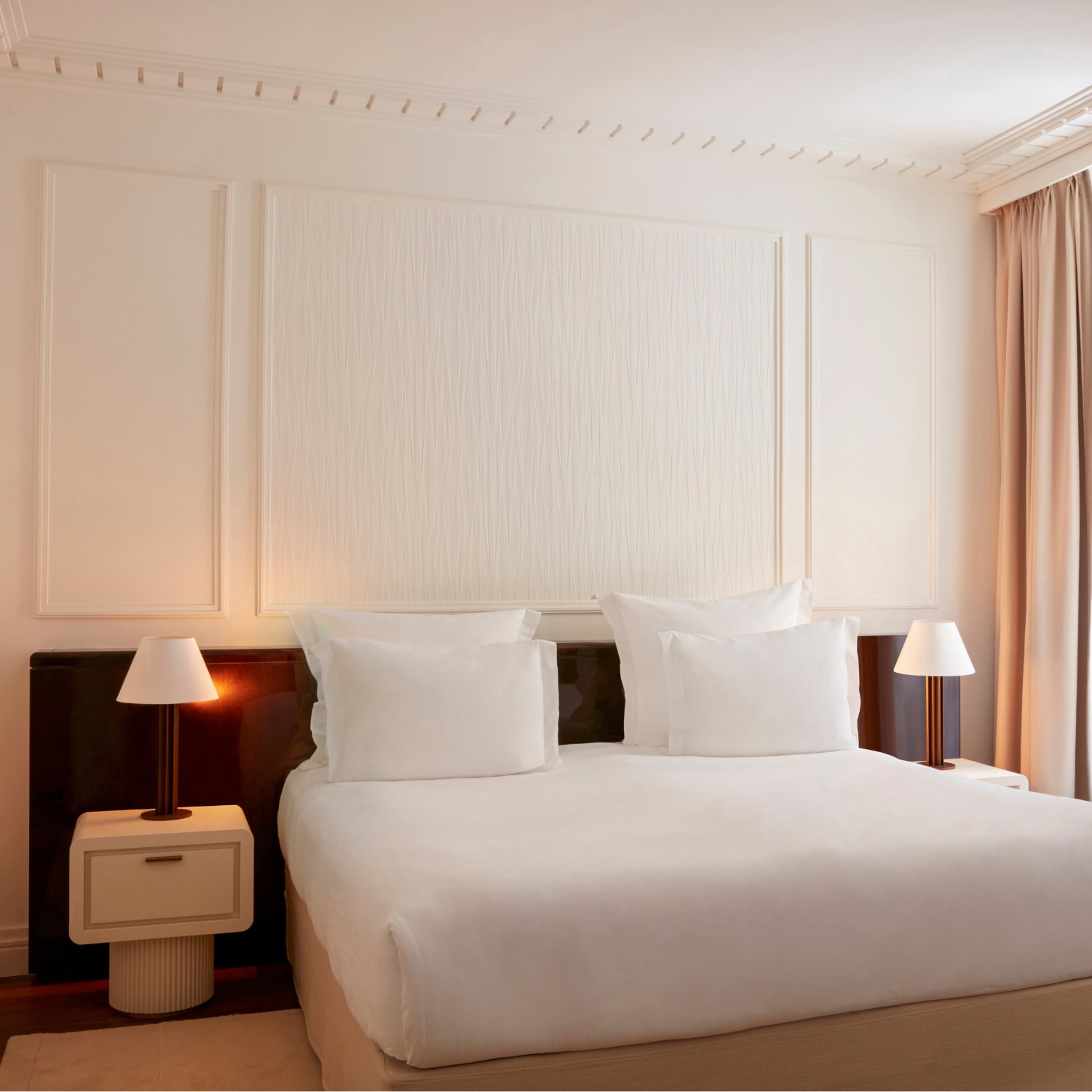 a king sized bed in a deluxe room at maison delano paris, with soft light from the lamps