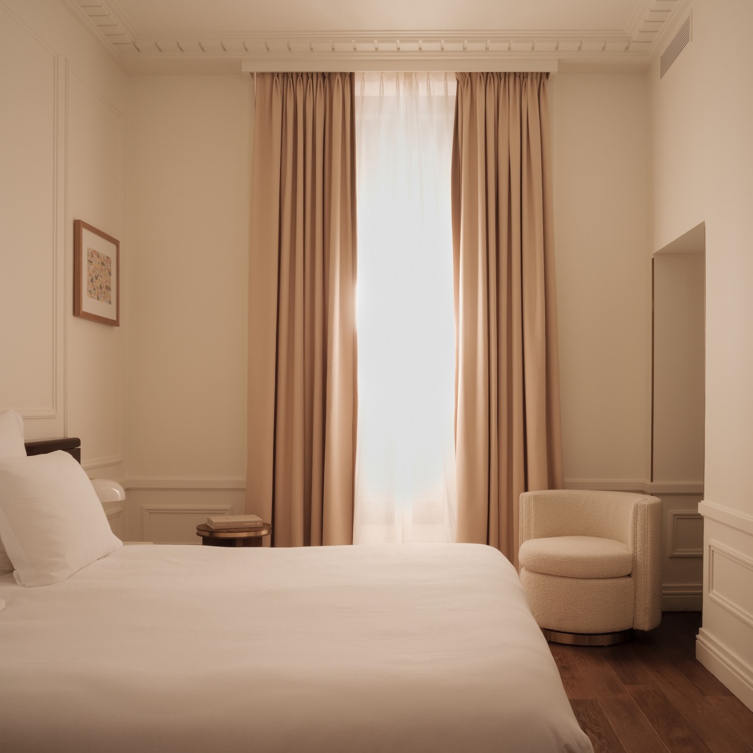 a side view of a king bed in the prestige room with drapes over the tall windows