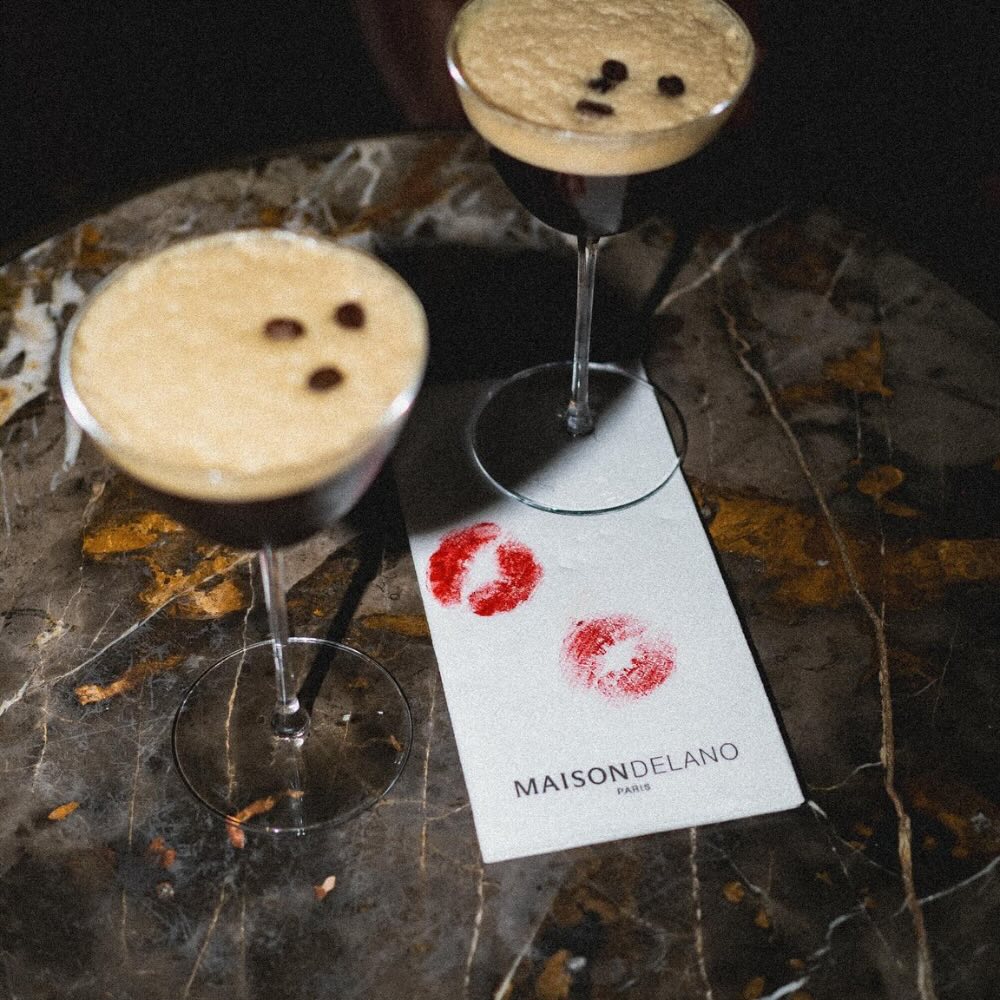 two espresso martinis sitting on table with a napkin with two lipstick stains