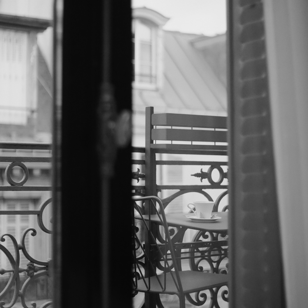 a view through a window to the terrace where a cup of coffee sits on a table