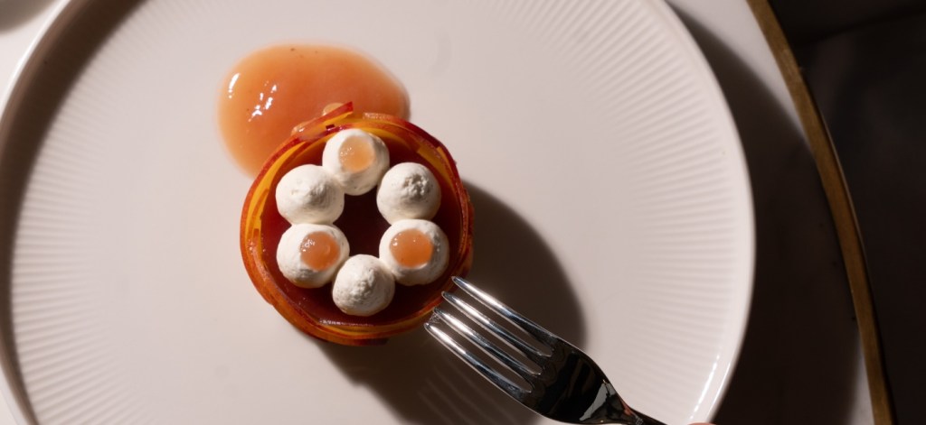 a fine dining dish at delano cafe, with a fork reaching to take a bite