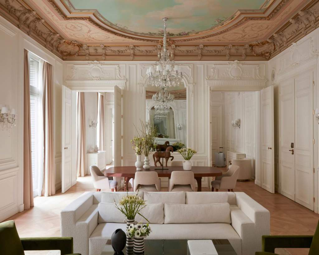 an ornate and elegant living room with a white couch and dining room table with a glass chandelier