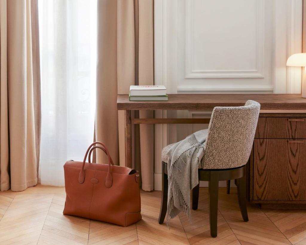 a desk with a grey chair and a tan leather bag next to it on the floor