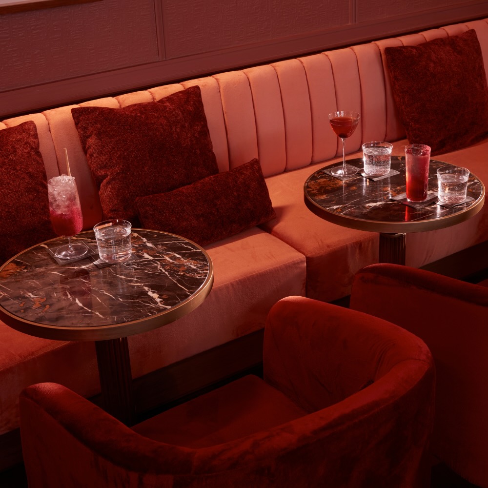 a seating area at delano bar with red velvet throw pillows