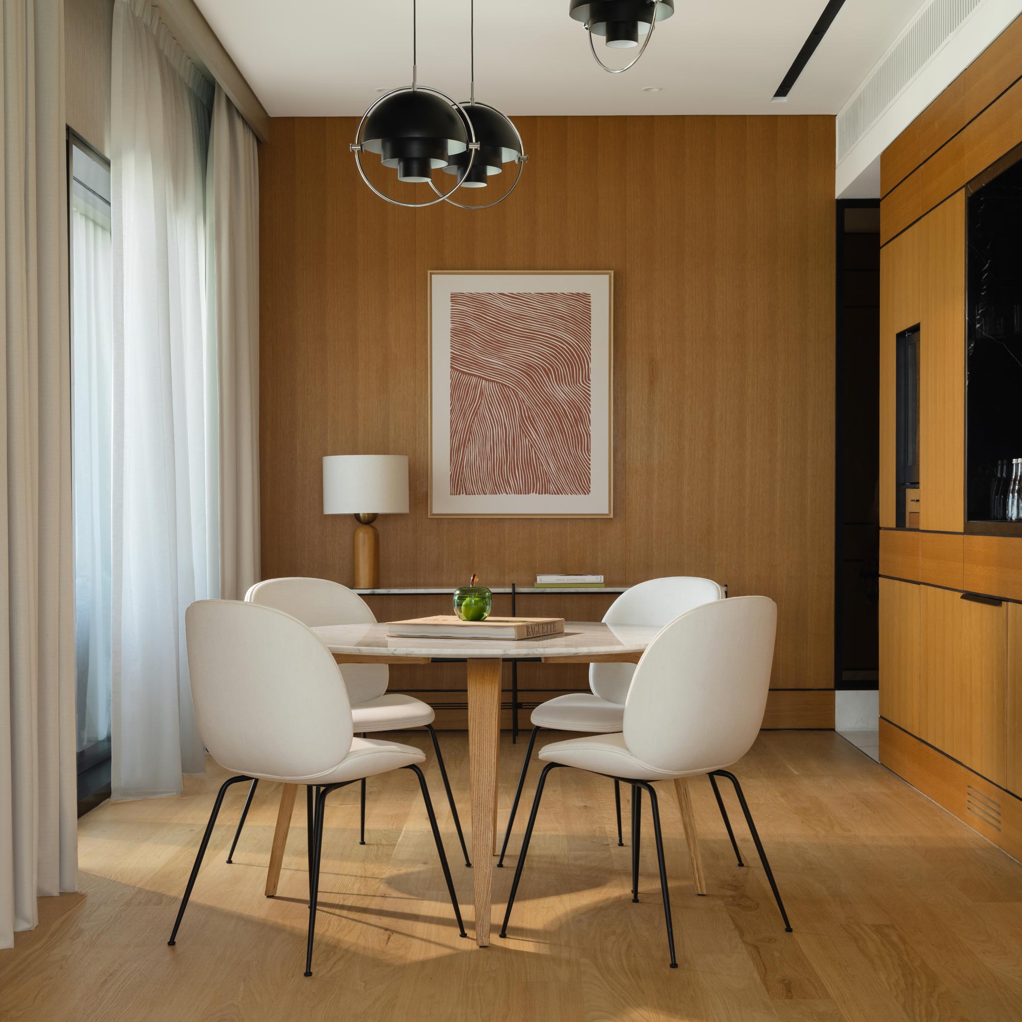 a dining space with a round table and 4 chairs under a modern chandelier