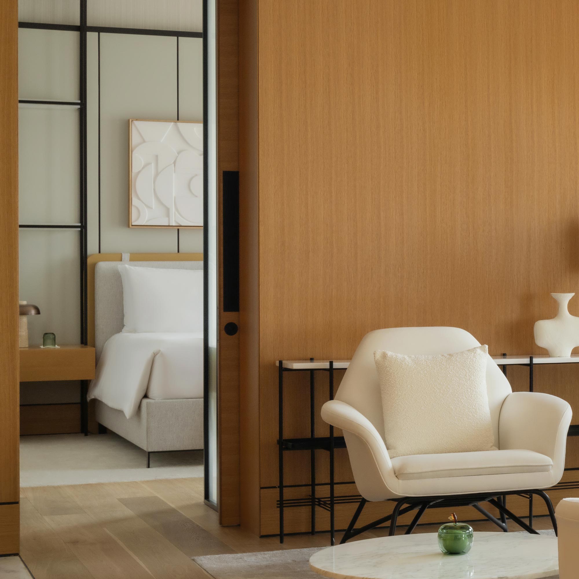 a view into the bedroom from the living space seating area with white chairs