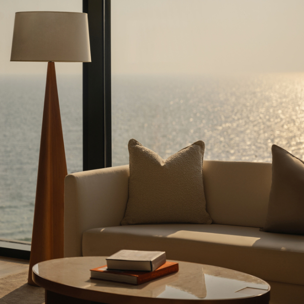 a white couch behind a coffee table and up against the windows