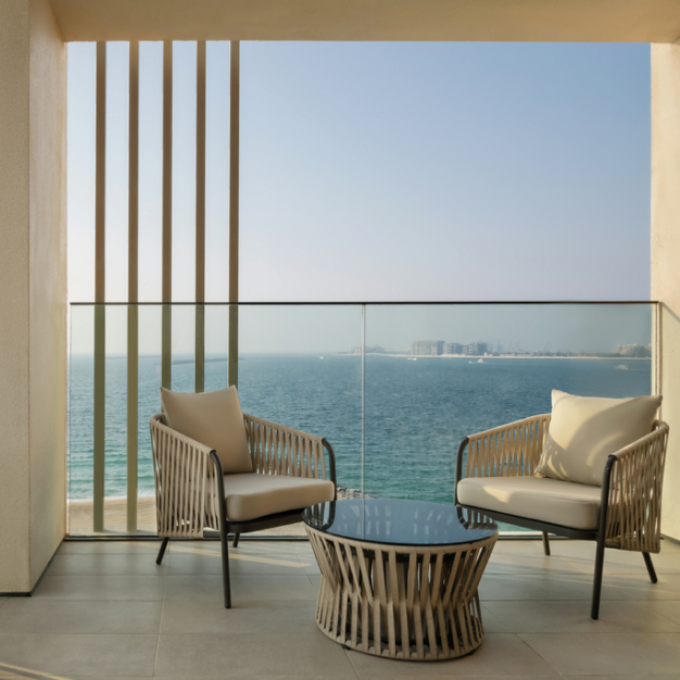 a patio with 2 chairs and coffee table with views of sea