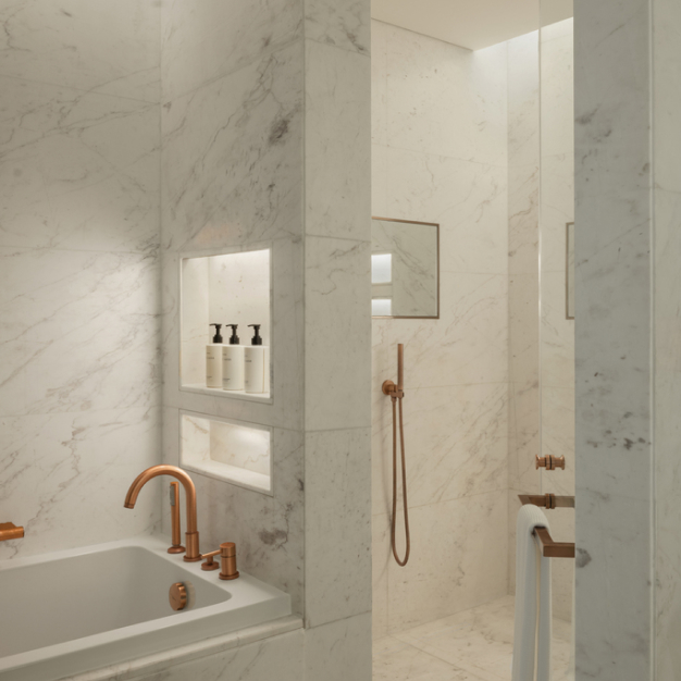 a marble white bathroom with separate shower and bathtub and amenities