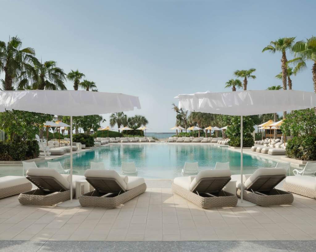 an expansive pool deck with lounge chairs and white umbrellas