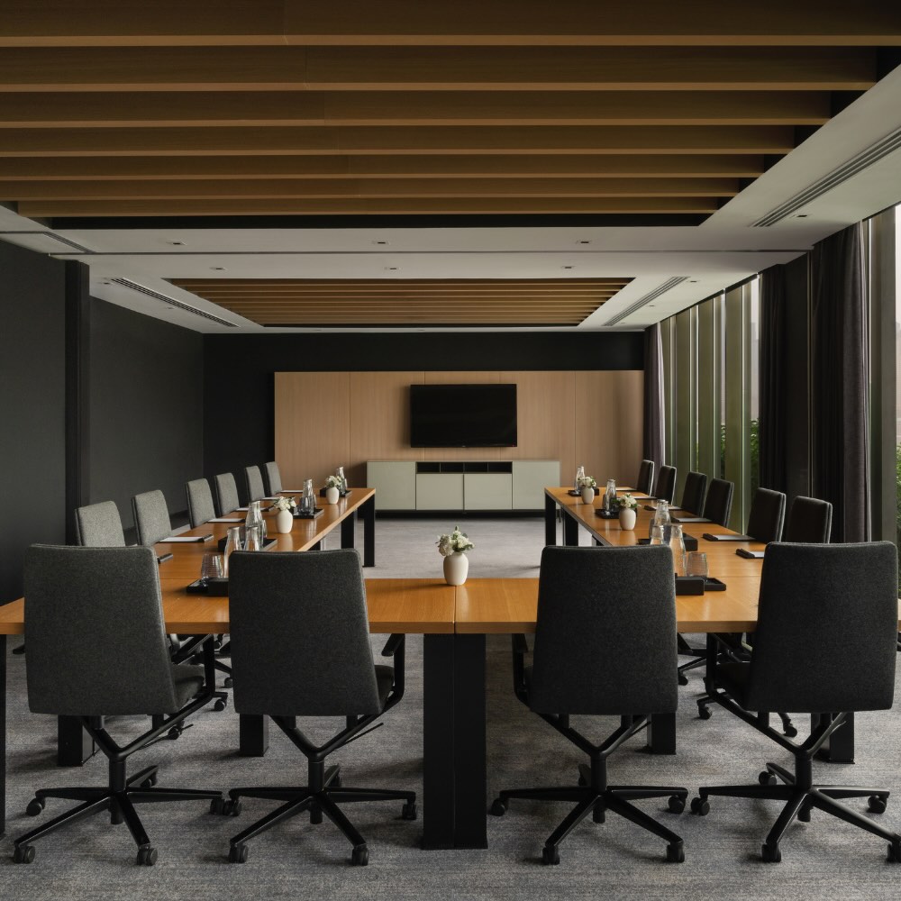 a classic board room with leather office chairs and u-shape table facing a screen