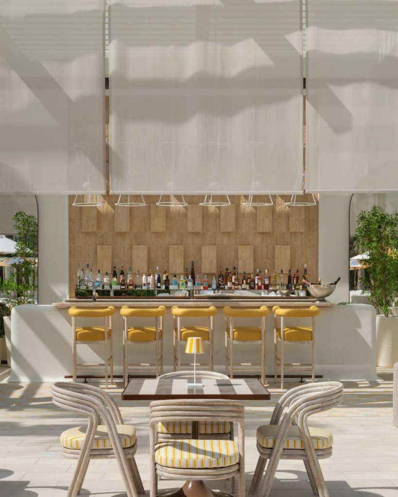 an outdoor bar at delano dubai with yellow high chairs