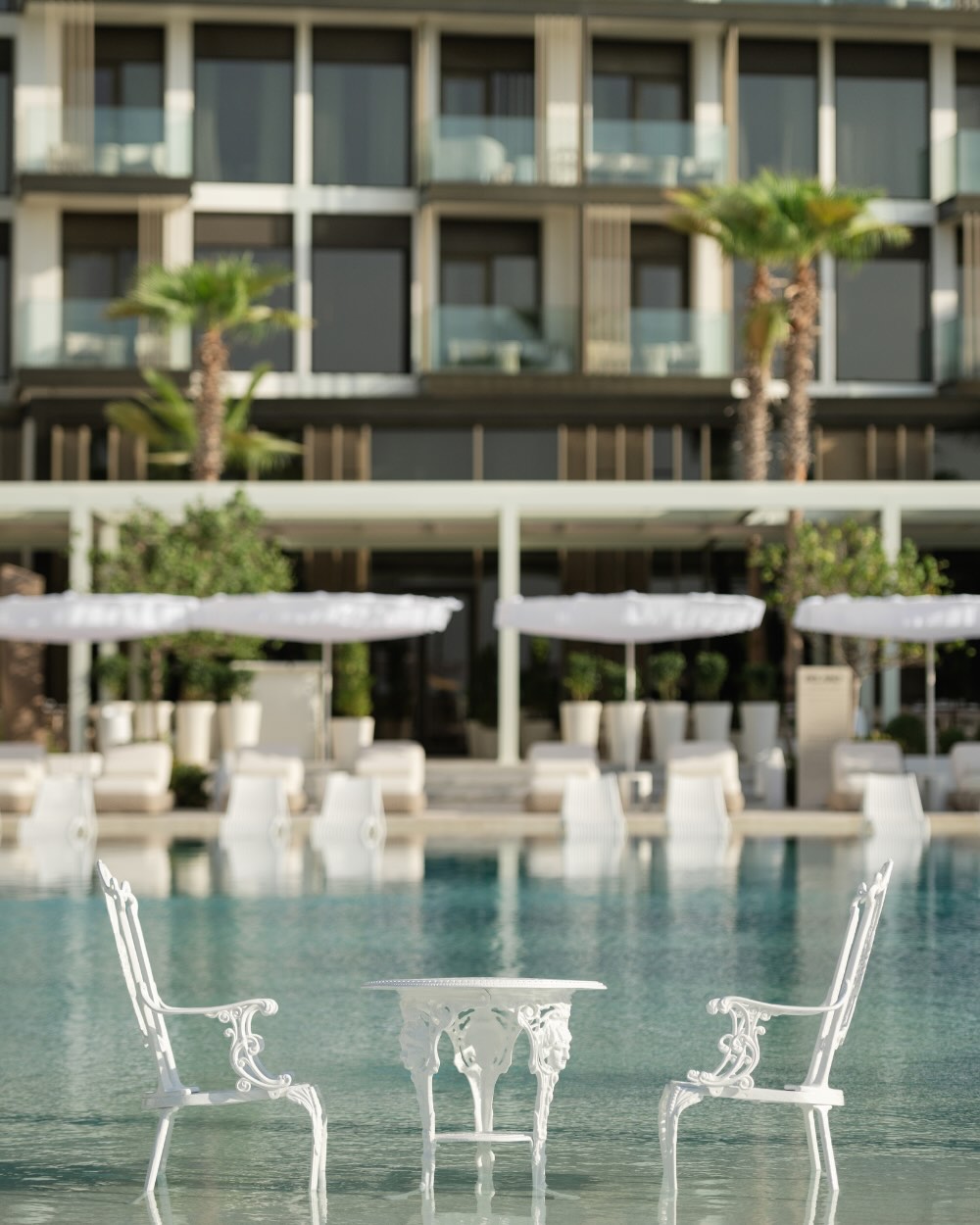 the iconic delano pool table and chairs in the delano dubai pool with the hotel in the background