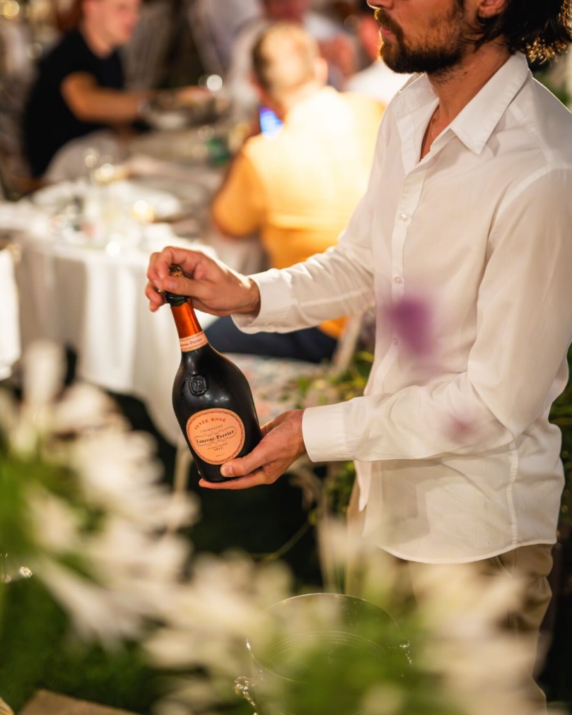 a waiter presenting champagne to the table at maison revka