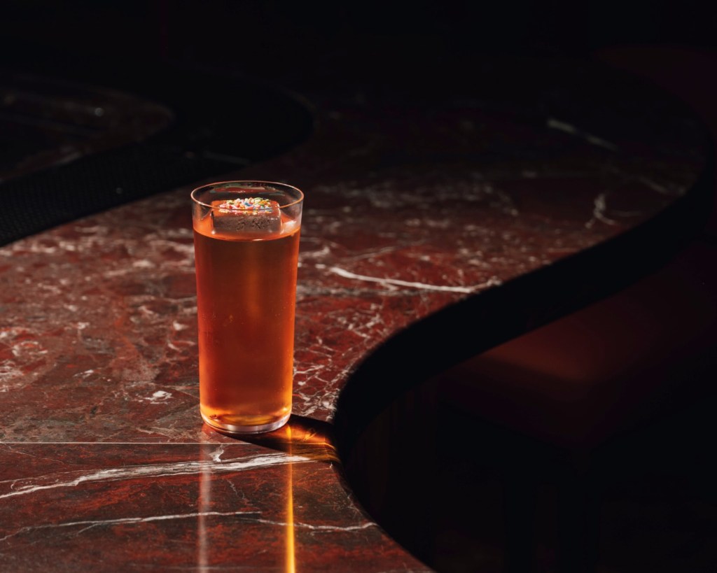 a cocktail garnished with a brownie on top of a marble bar