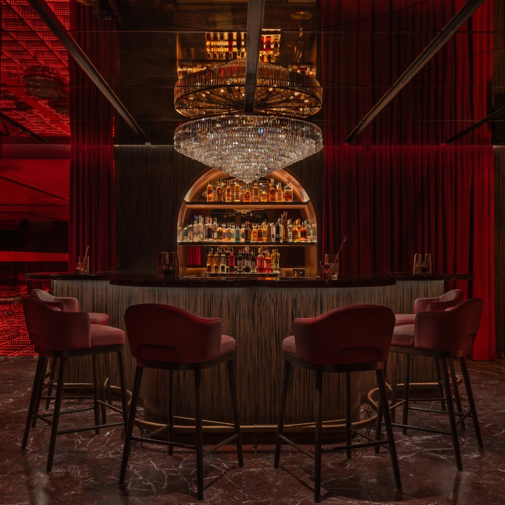 the rose bar at delano dubai with a glass chandelier and rose colored seating and walls