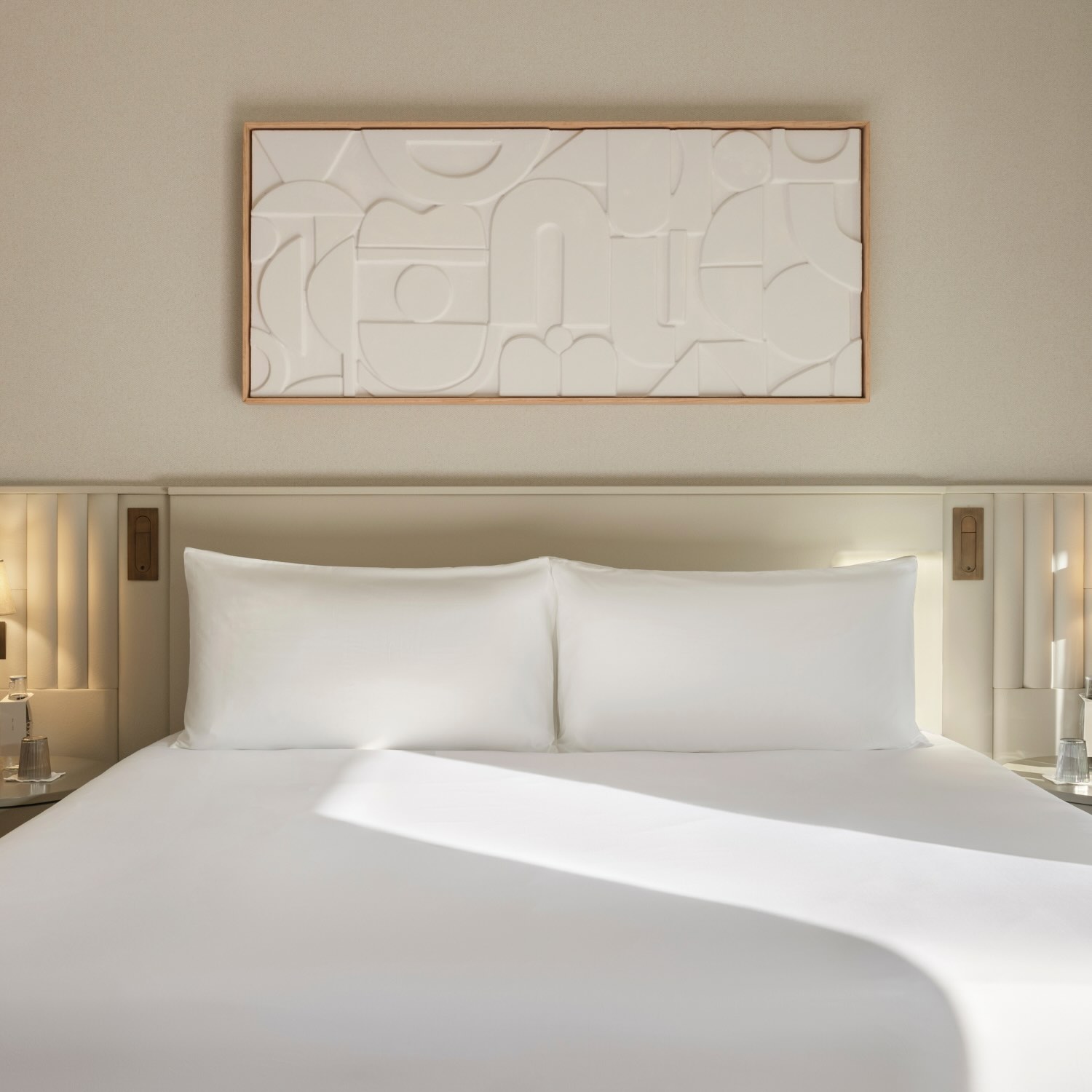 a king size bed with a natural headboard and large artwork above on the wall