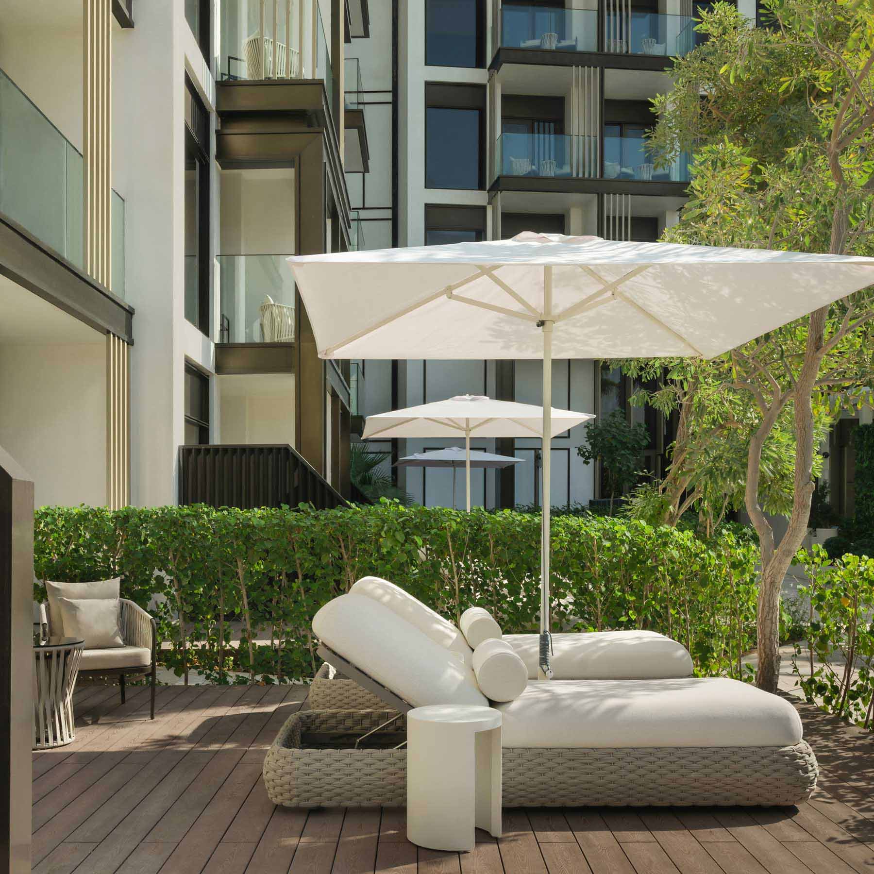 a garden balcony with two luxurious lounge chairs with a white umbrella