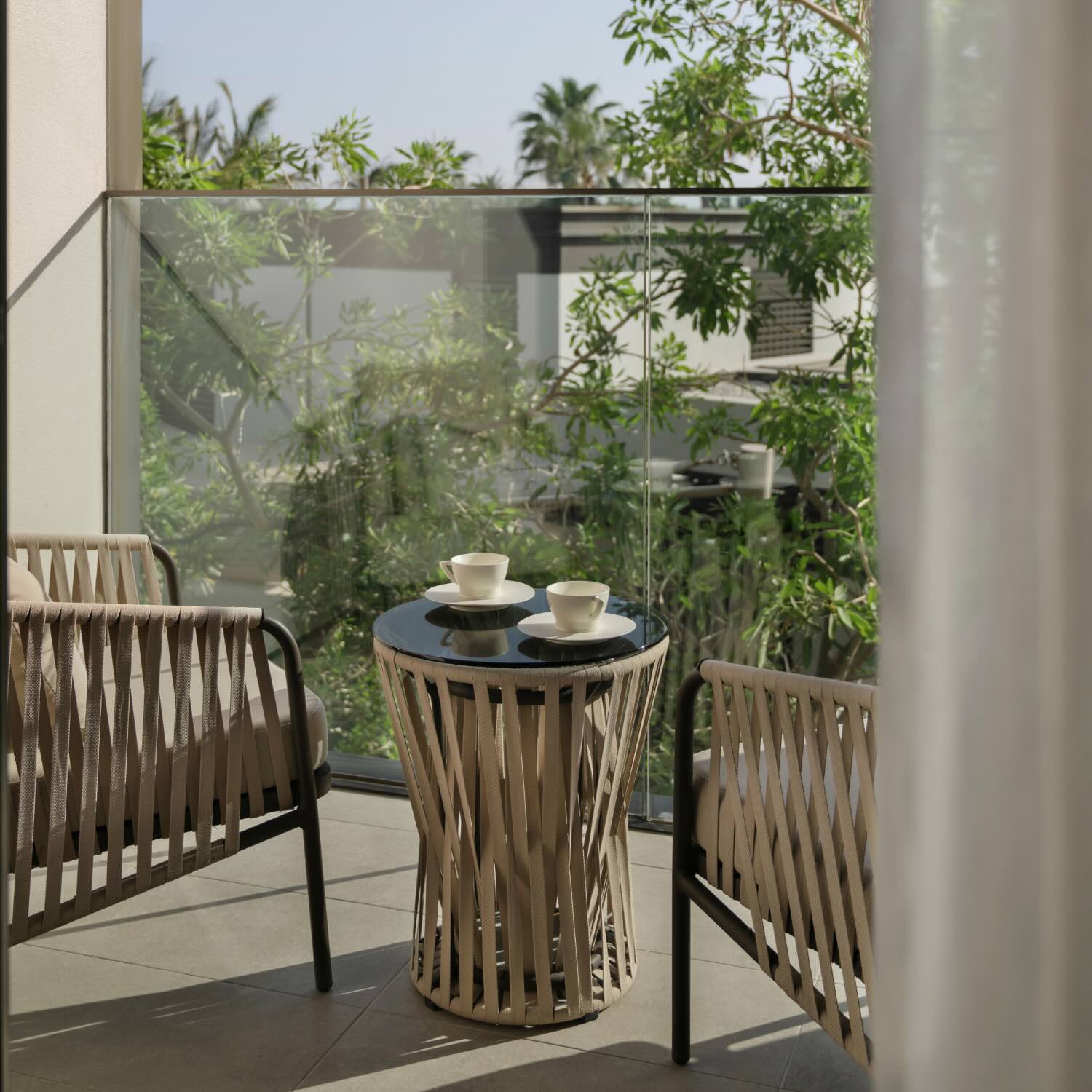 two woven chairs on the deck with coffee placed on a table in between them