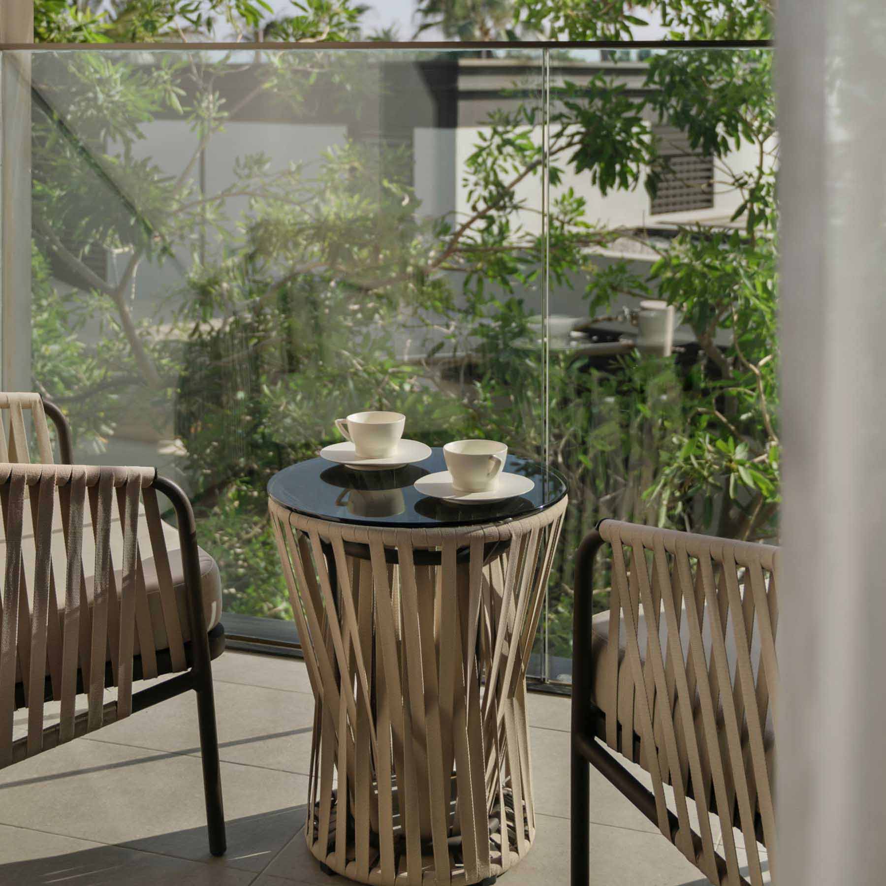 a balcony with two chairs and a small side table which has two coffees on top