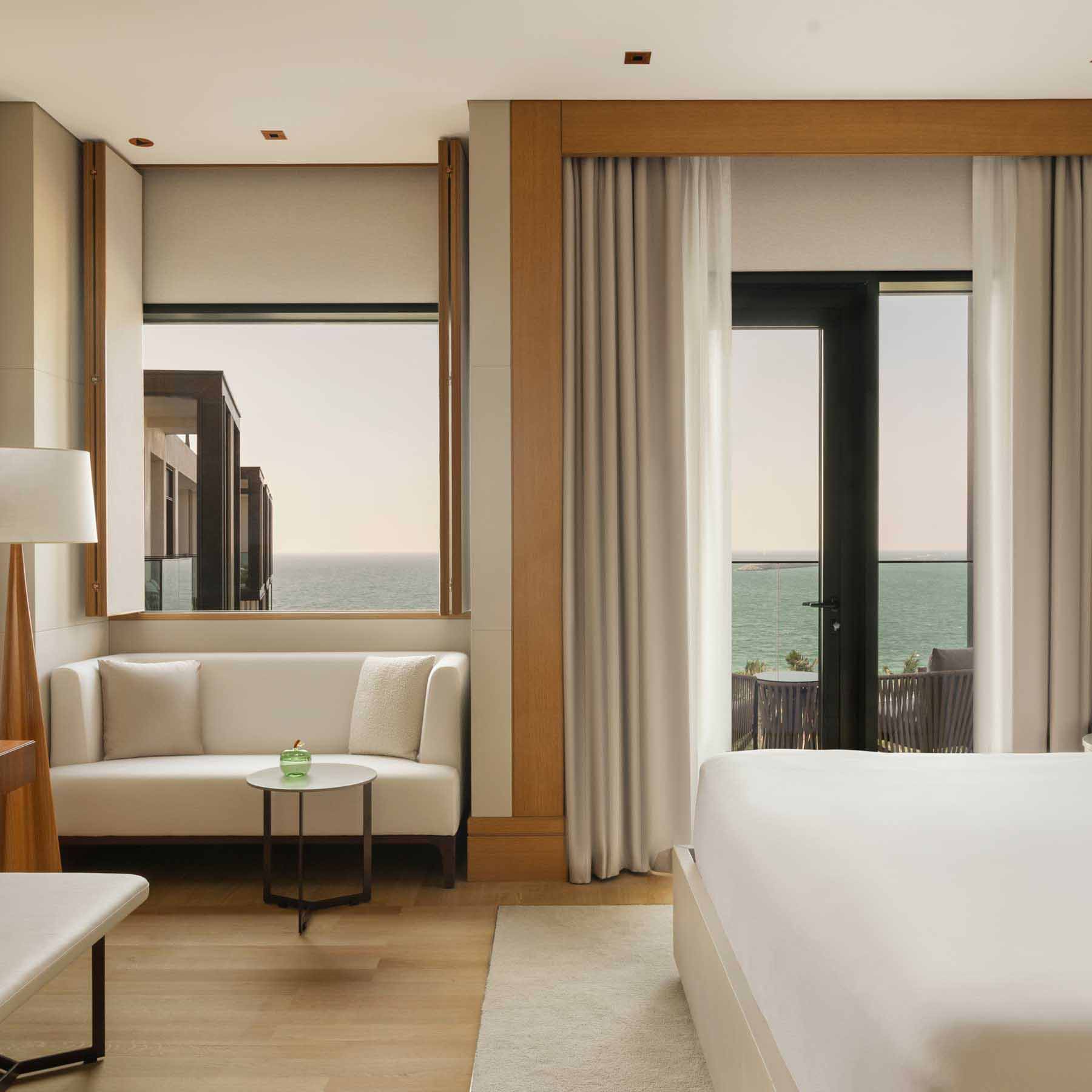 the rising light sea view guestroom with natural light a king bed and sitting area with a white couch