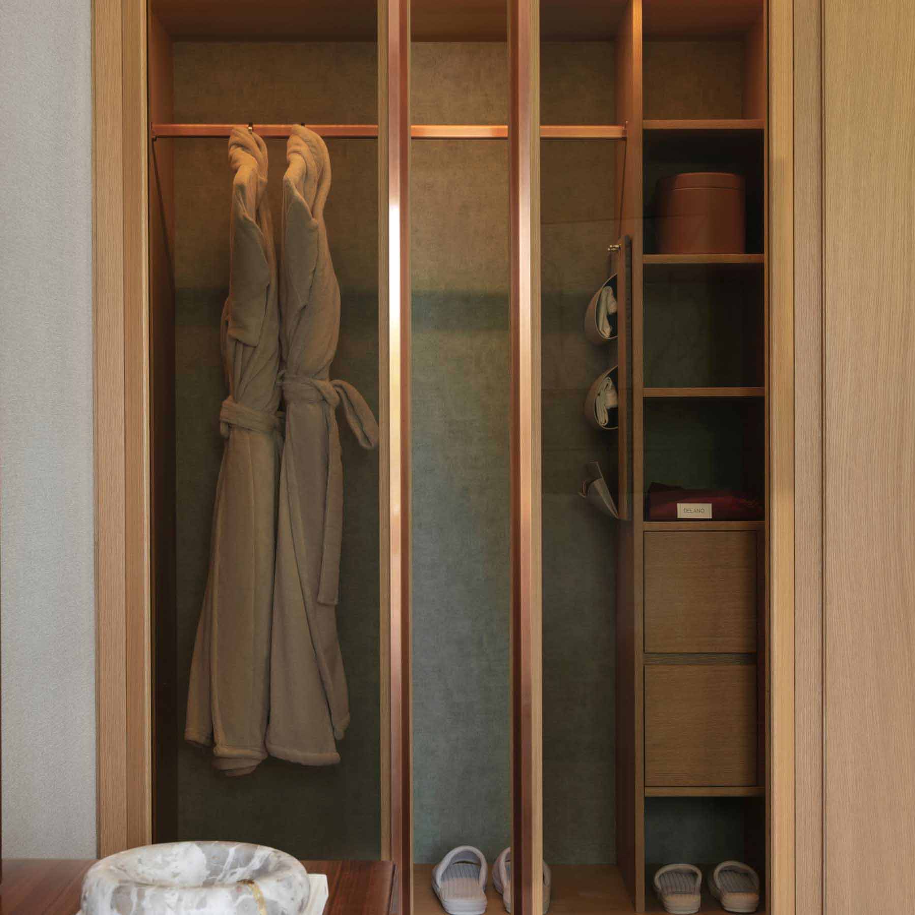 the closet armoire in the room with robes hanging