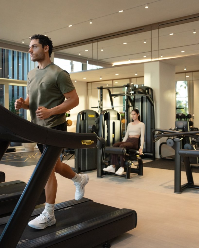 a man running on the treadmill with woman working out behind him