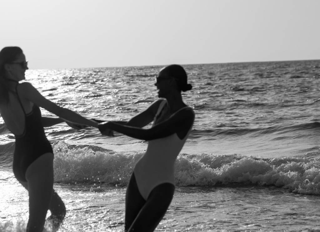 a black and white image of two women on the beach