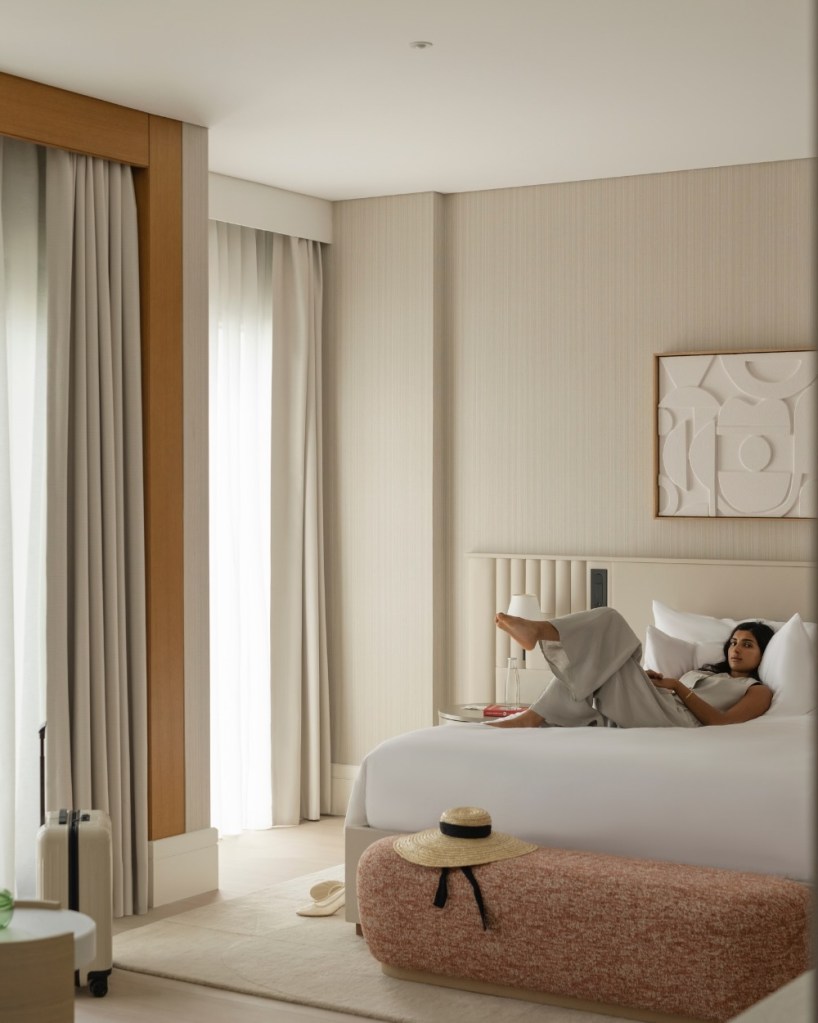 a woman lounging on the bed in a suite at delano dubai