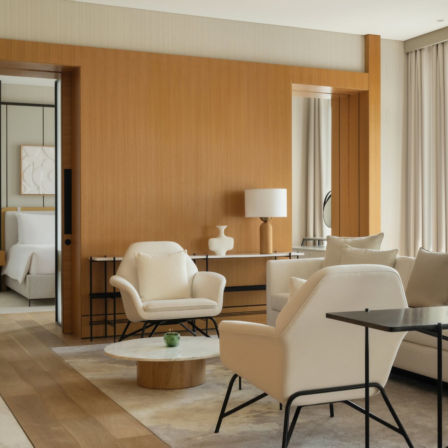 a living space with a white couch, two white chairs and a marble coffee table