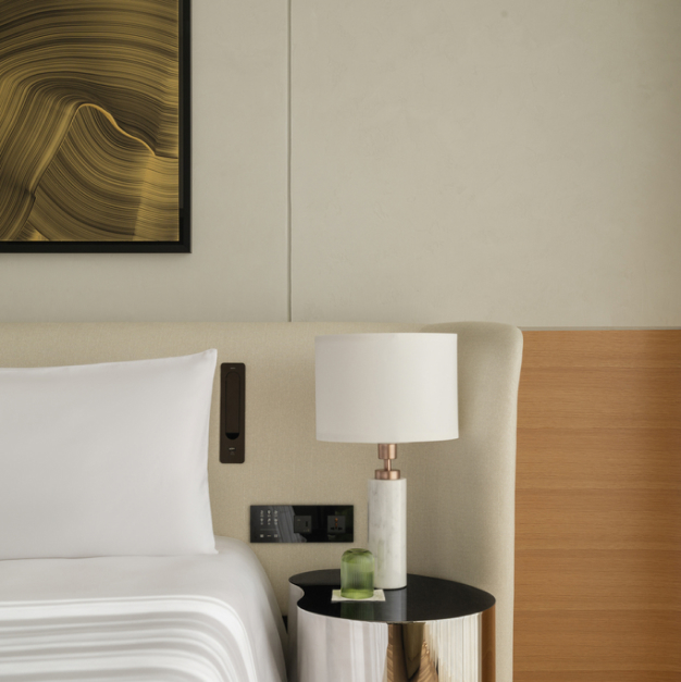 a close up of a bedside table with a small white lamp