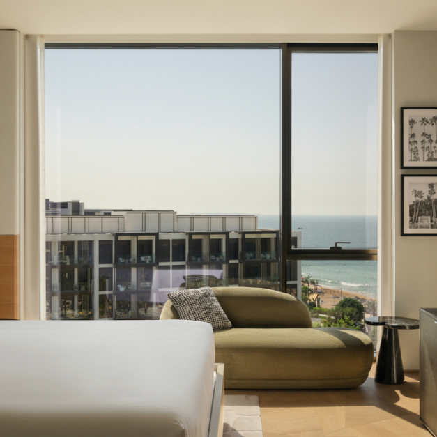 the side view of a bed with a green lounging chair up against the window