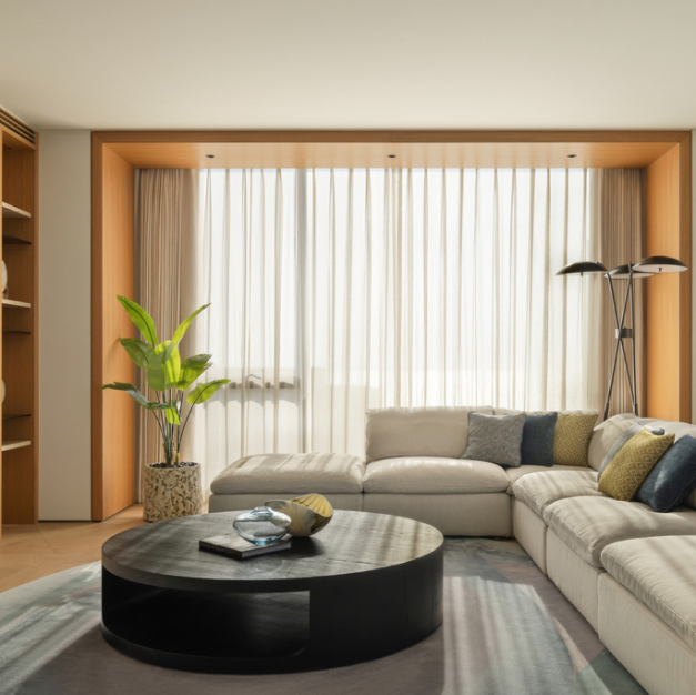 a smaller living space with a white sectional couch and black circular coffee table