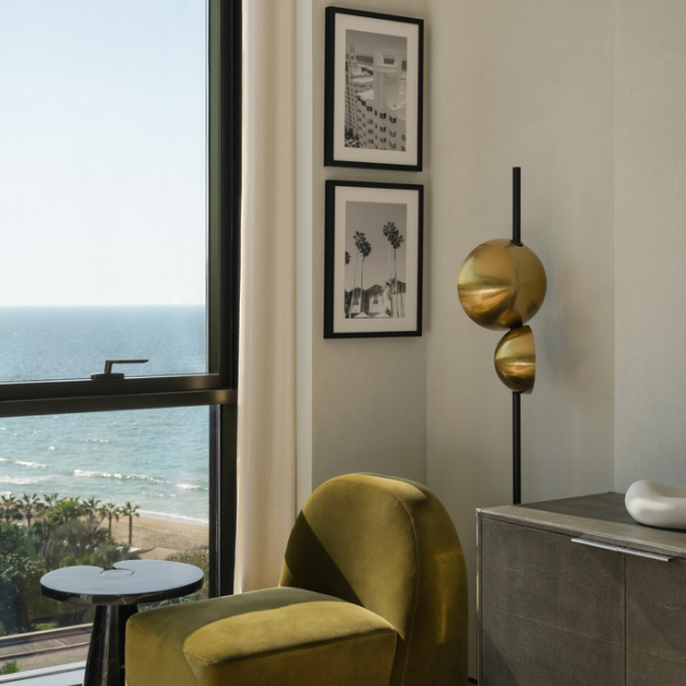 a green chair and side table against the window with views of the sea