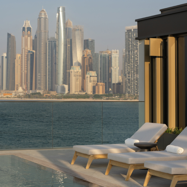 an outdoor terrace with views of the sea and the dubai skyline