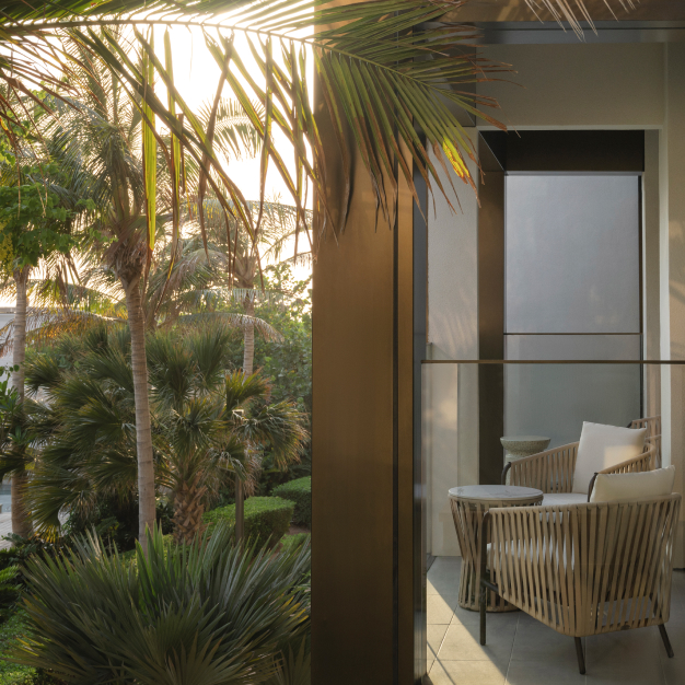 a patio space with woven chairs and views of greenery