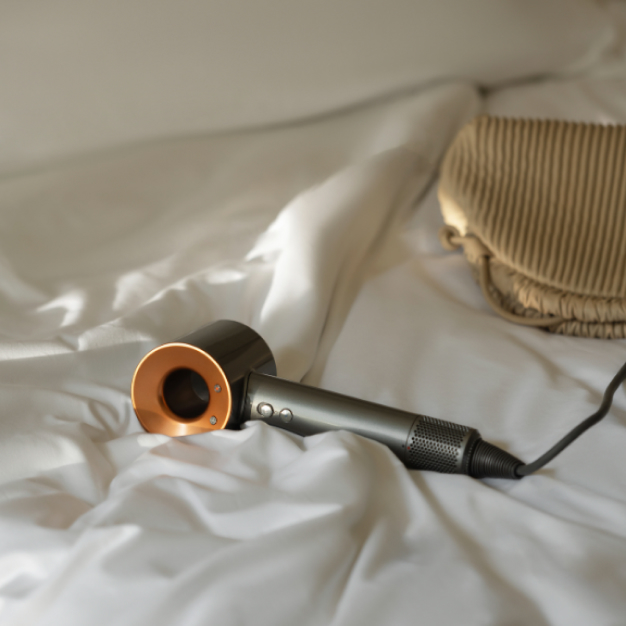 a dyson hair dryer laying in sheets