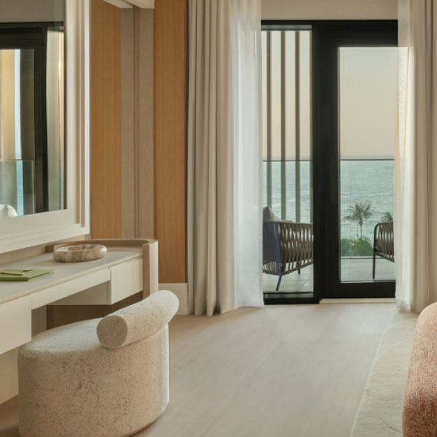 a view of the vanity in the bedroom and the glass doors that lead to the patio with views of the sea