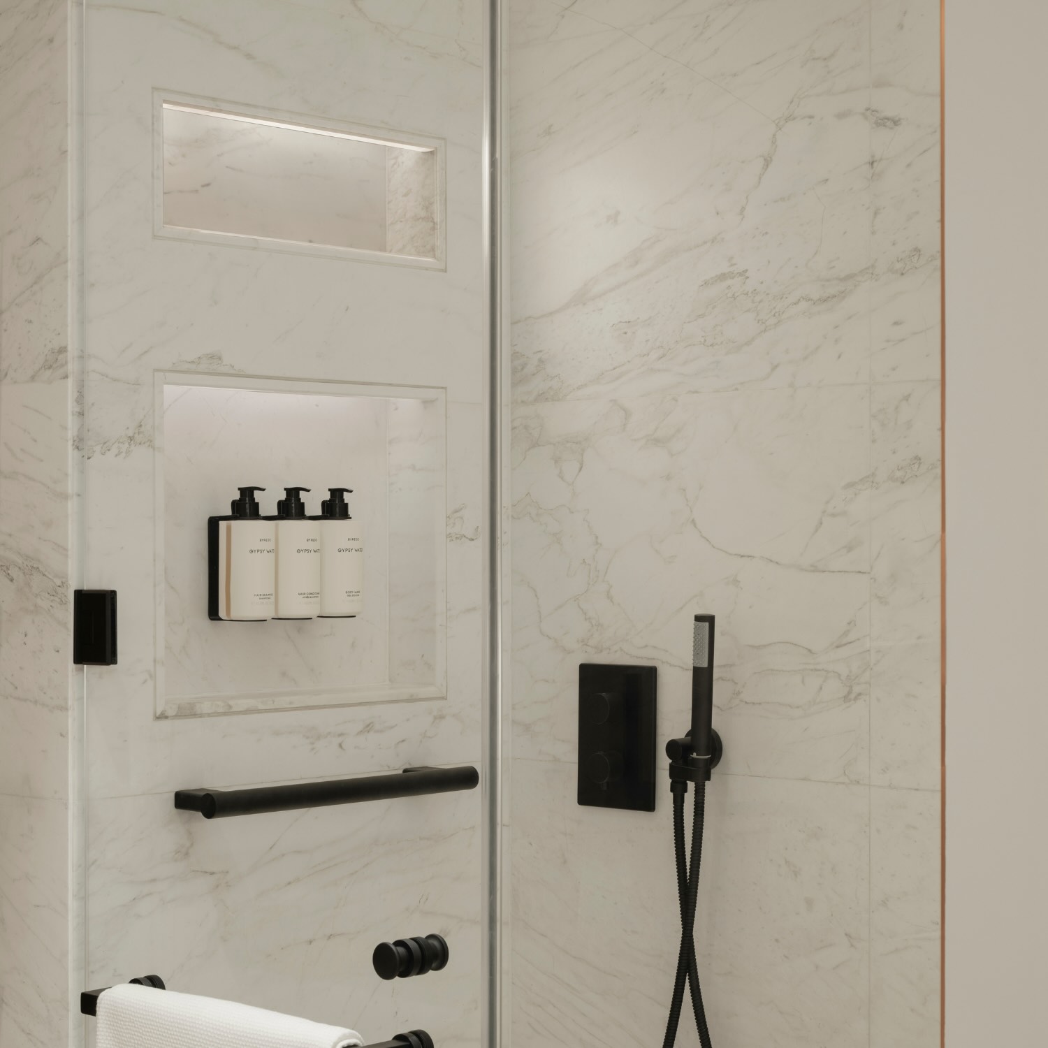 a marble shower with glass doors and black finishes