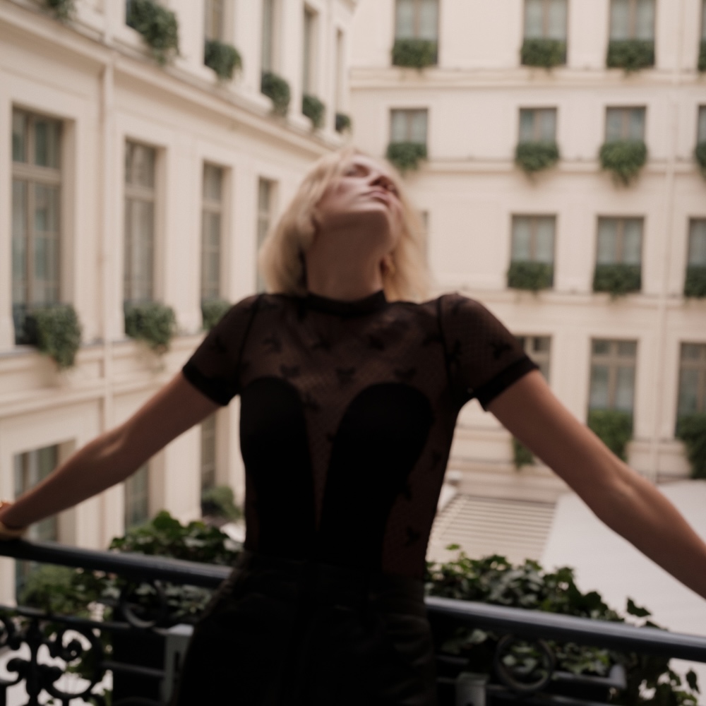 a woman standing on against a rail in a parisian courtyard