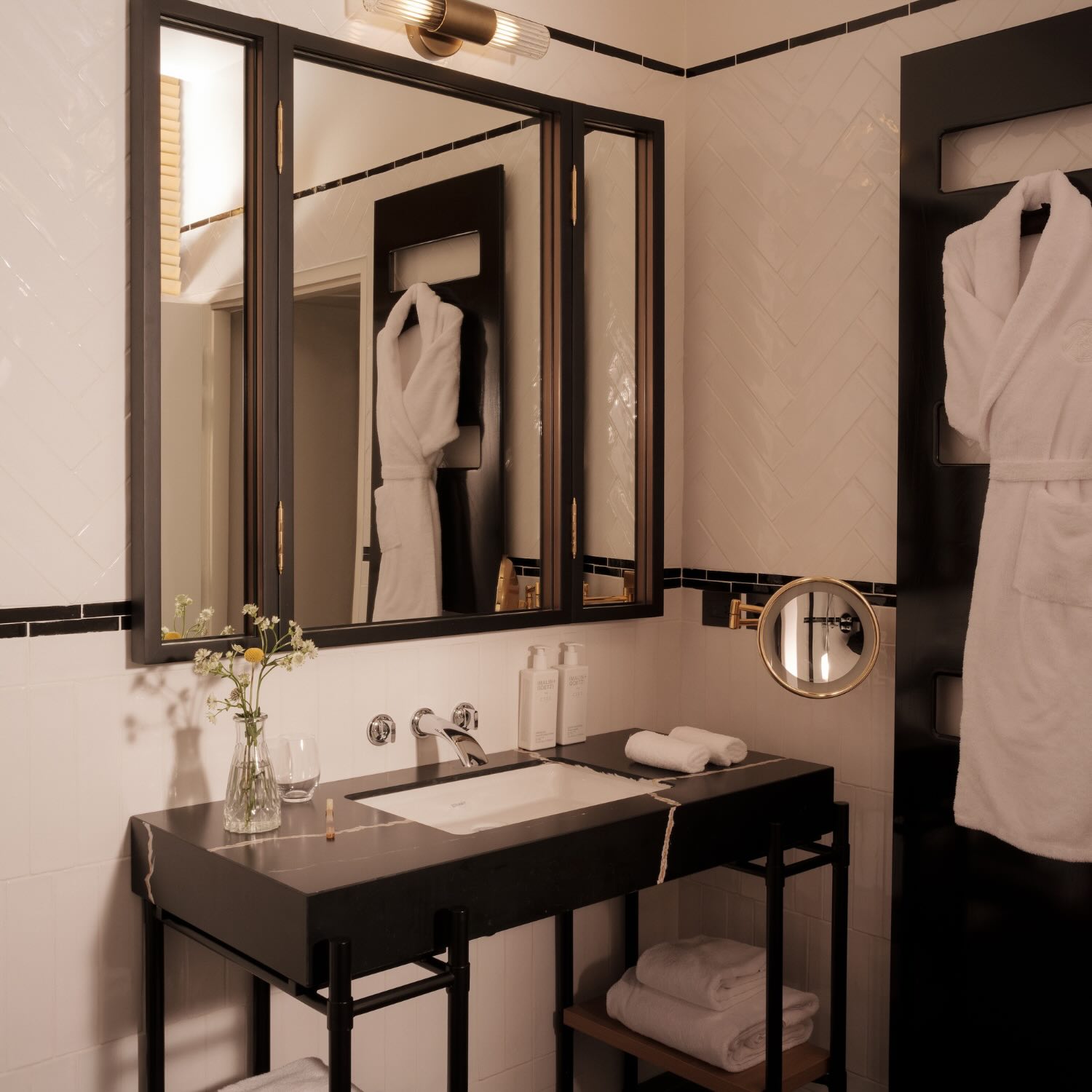 a bathroom in a room at maison delano paris with a black marble vanity and bathrobe hanging from the door