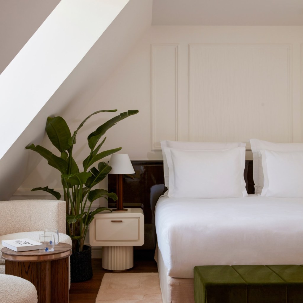 a bedroom with a bedside tables, two chairs and a large plant.