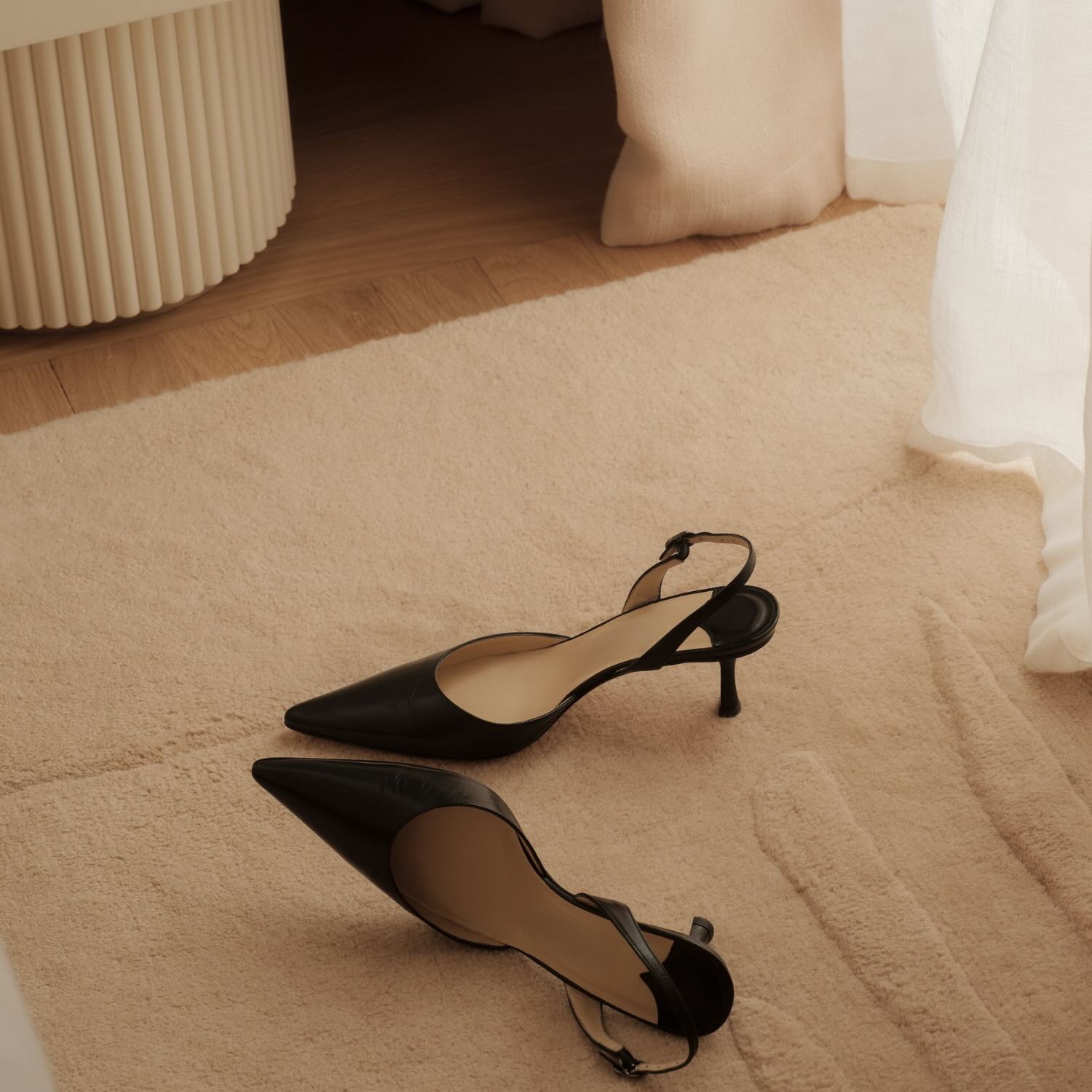 a pair of black closed toed heels on a white rug