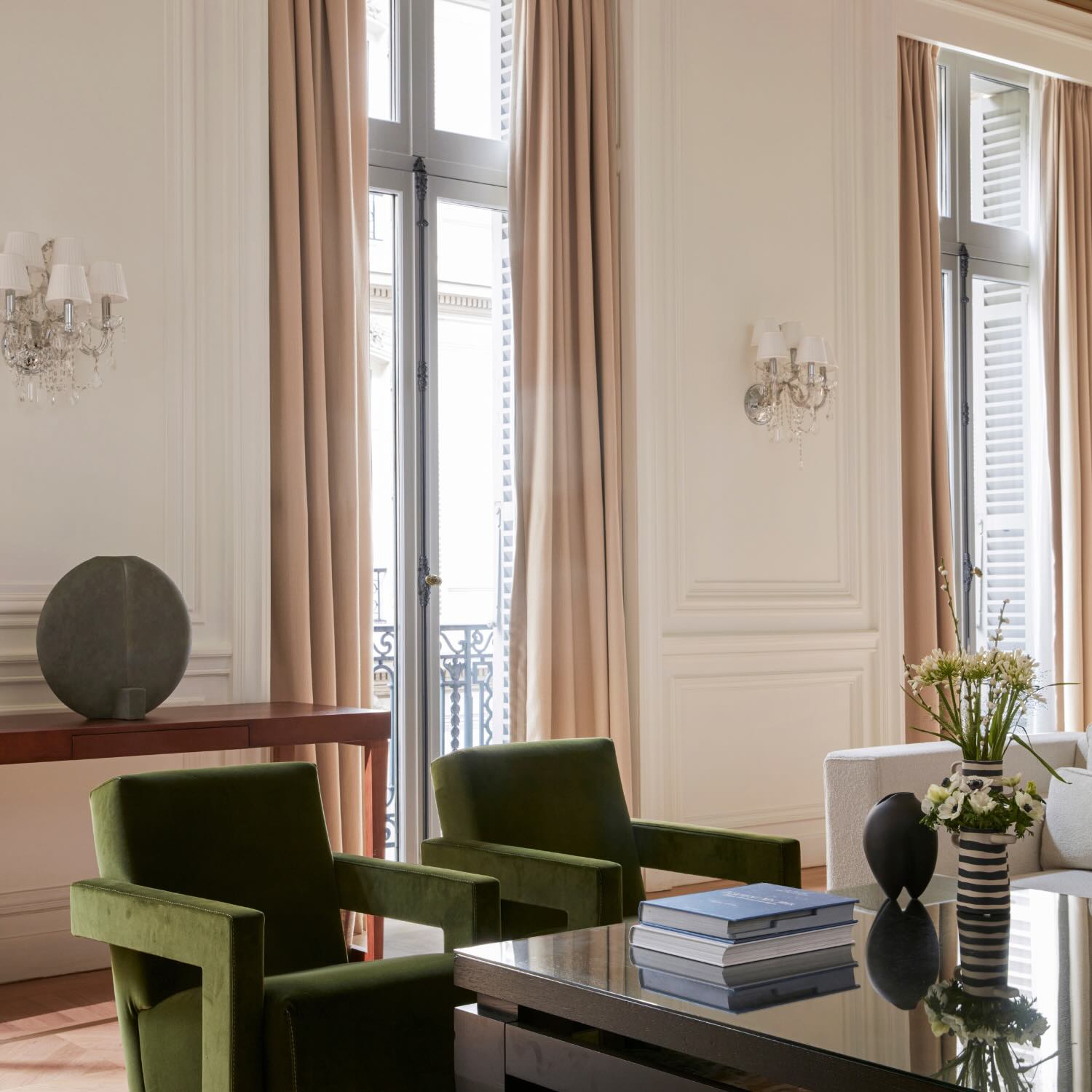 a grand living room in the presidential suite with two green velvet chairs against a black coffee table