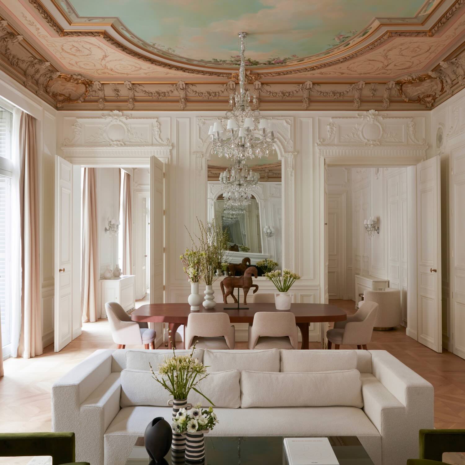 a grand living room with a white couch and glass chandeliers