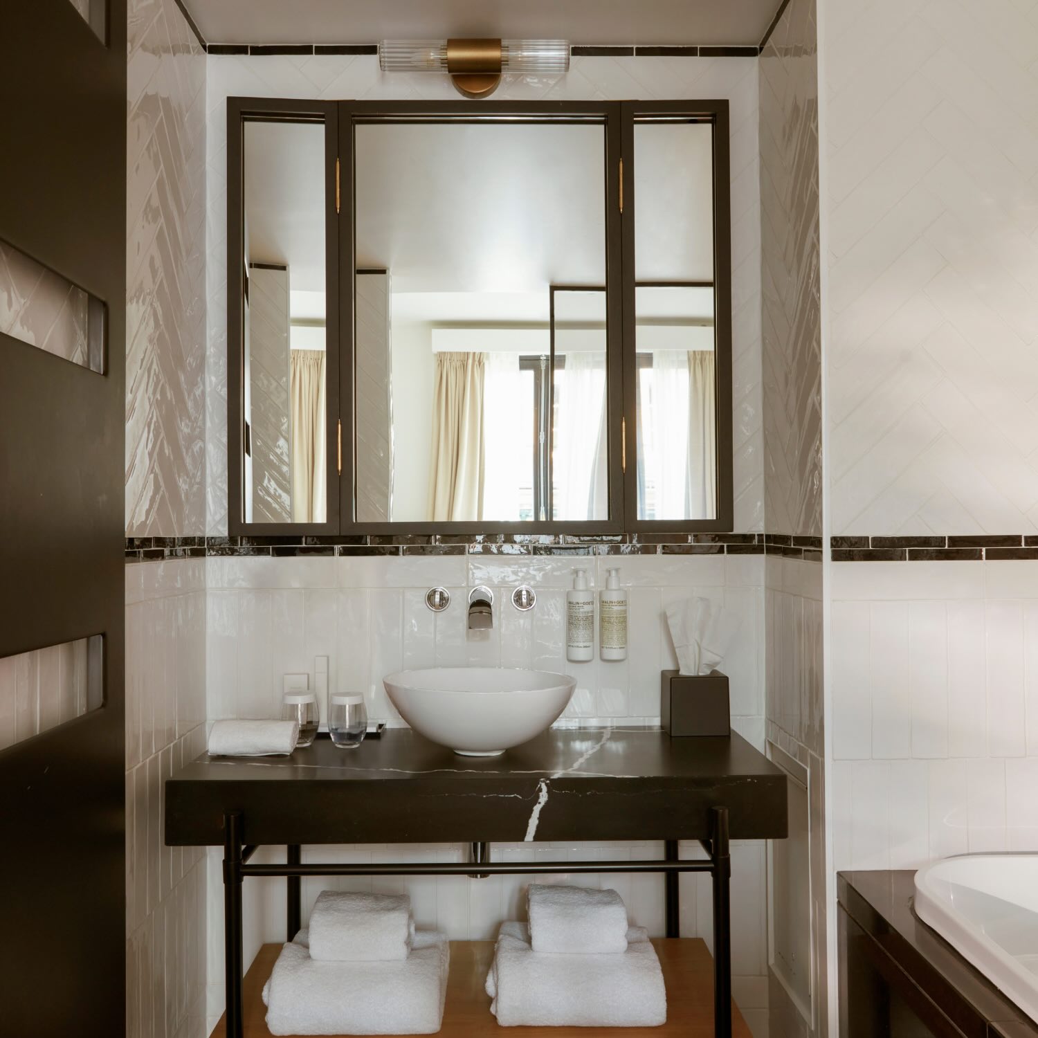 a bathroom with black and white tile and a large bowl white sink