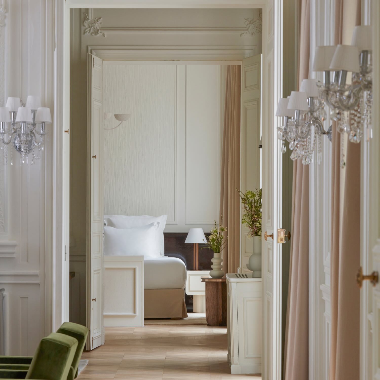 the view of a bedroom from the hallways with glass scones lining the wall