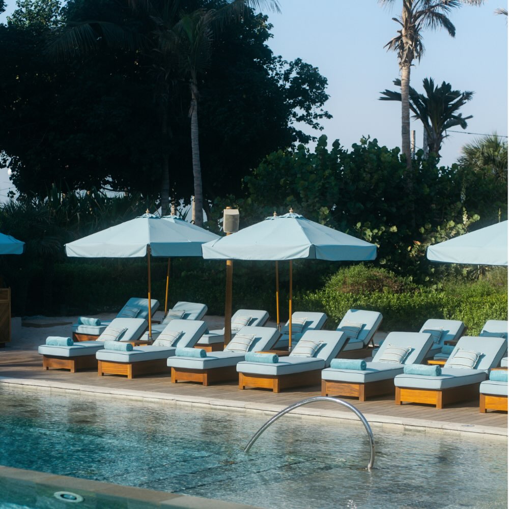 the pool at la cantine beach with blue umbrellas and lounge chairs