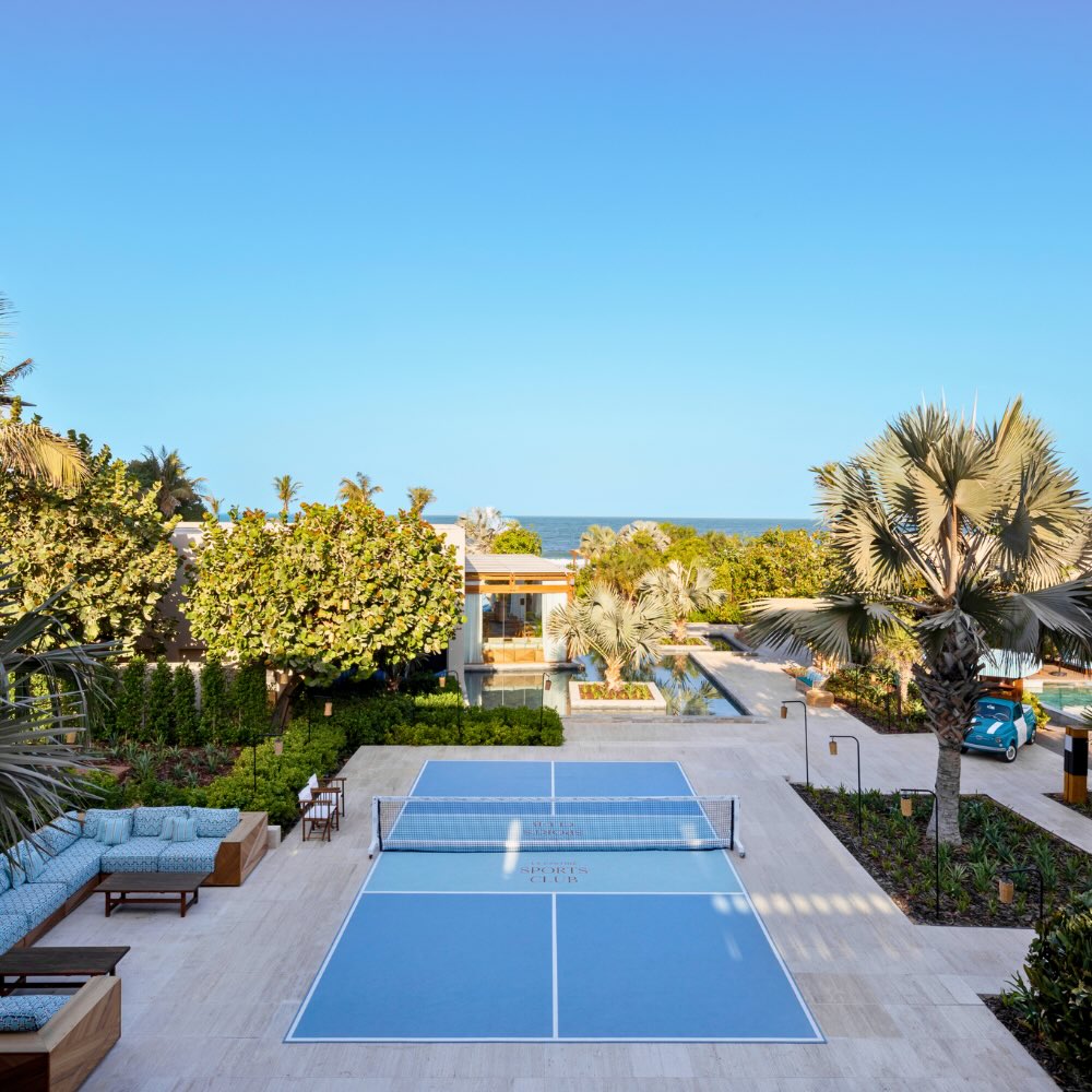 an aerial view of the la cantine venue with a pickleball court, plush seating and views of the ocean