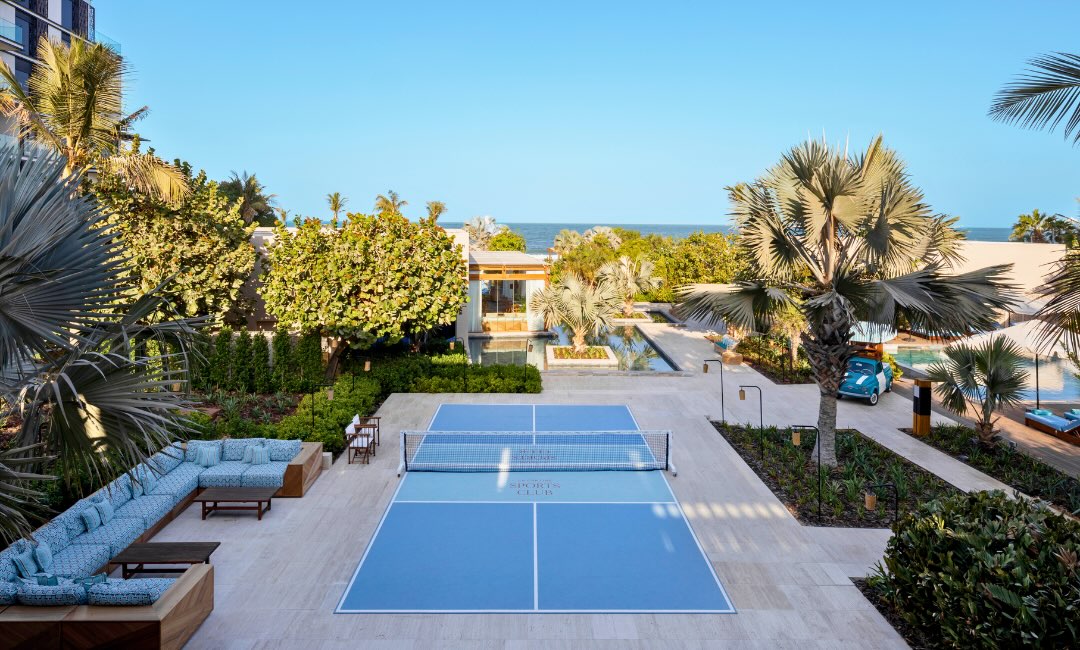 an aerial view of the la cantine venue with a pickleball court, plush seating and views of the ocean